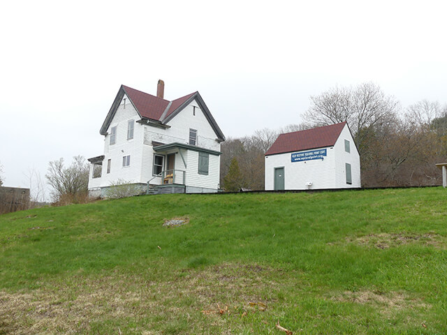The Lighthouse Keepers house and barn up the grassy hill from Squirrel Point Light in Maine